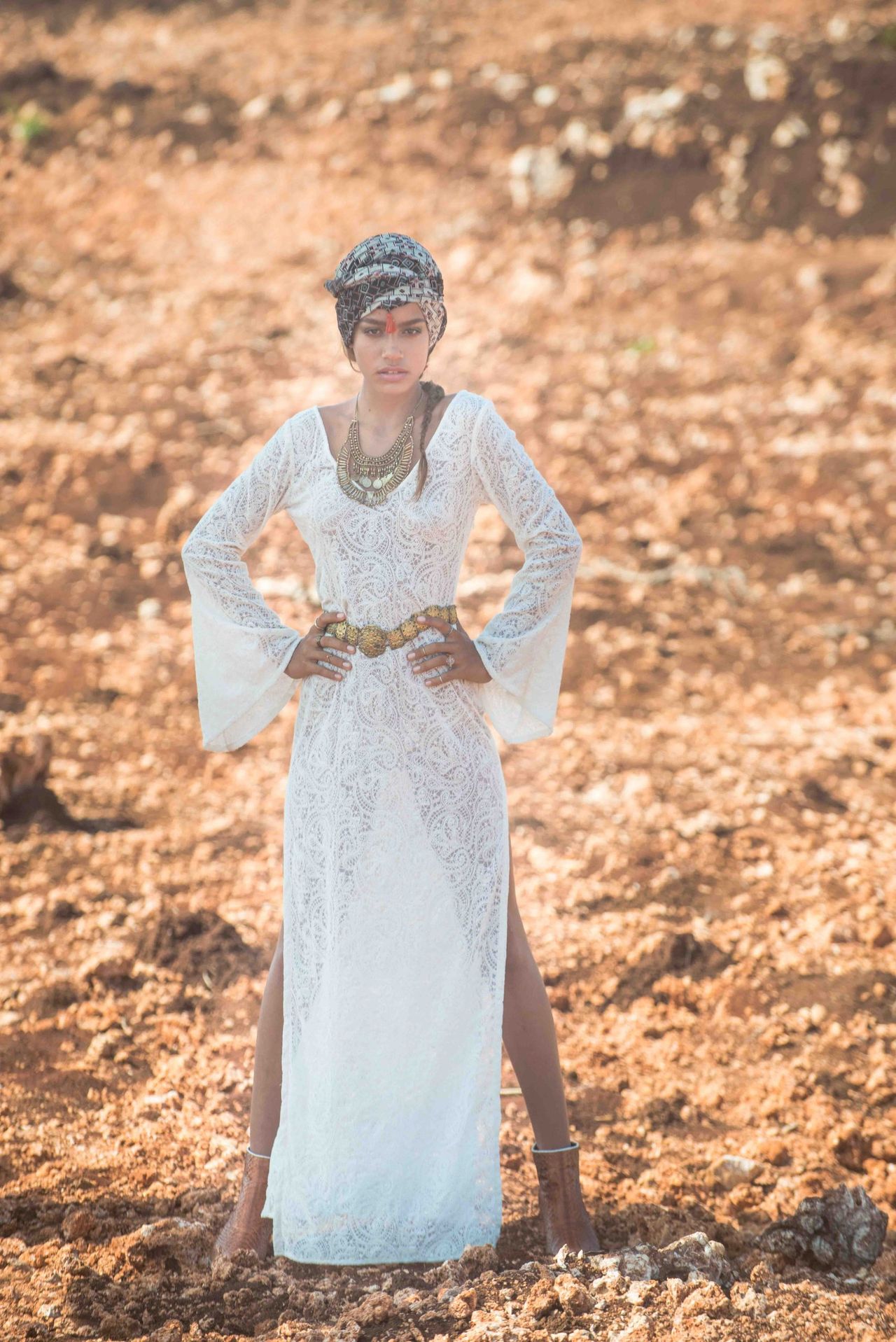 Woman in a white dress and headscarf standing on dry earth
