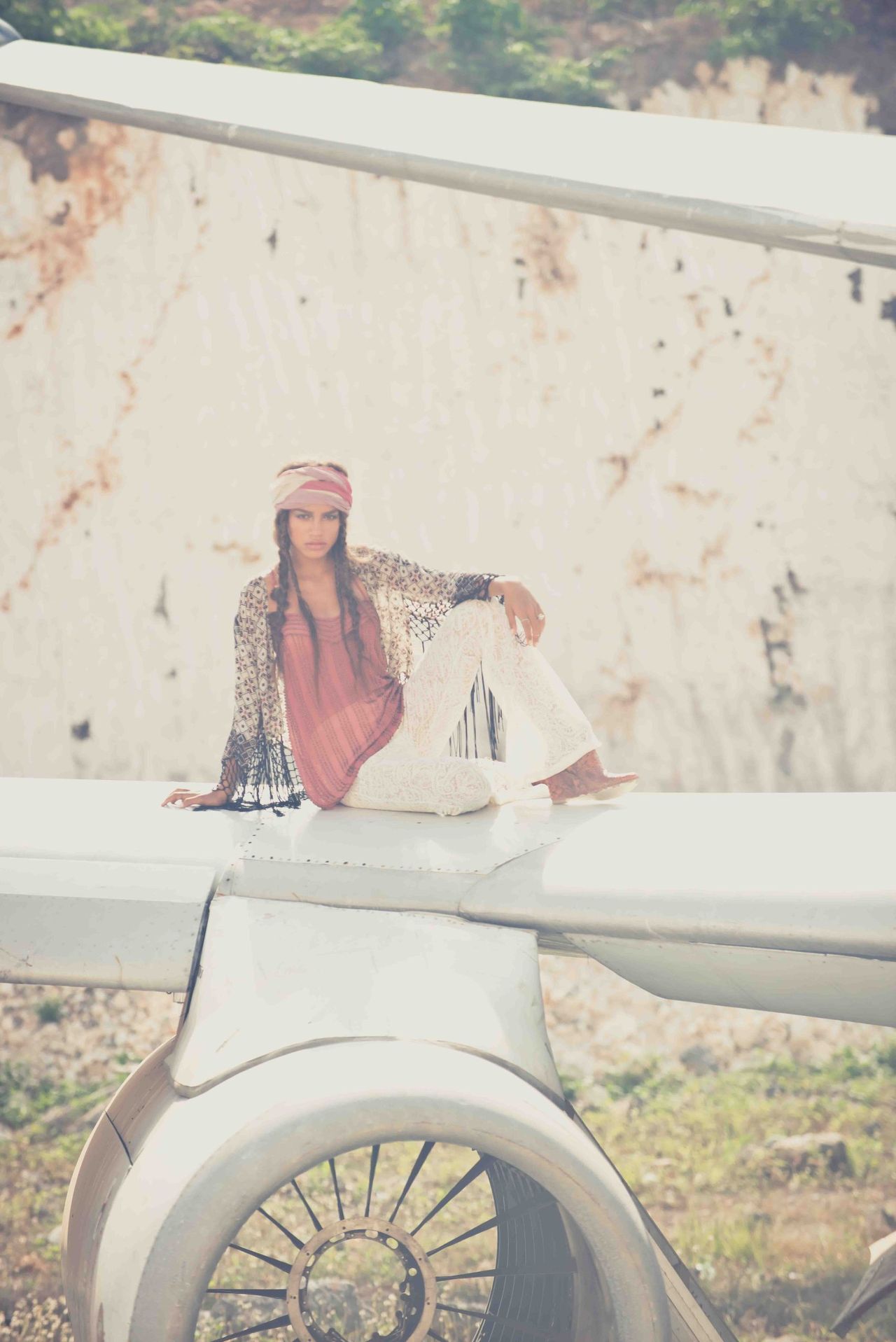 Woman in a headscarf seated on the bonnet of a white vintage car