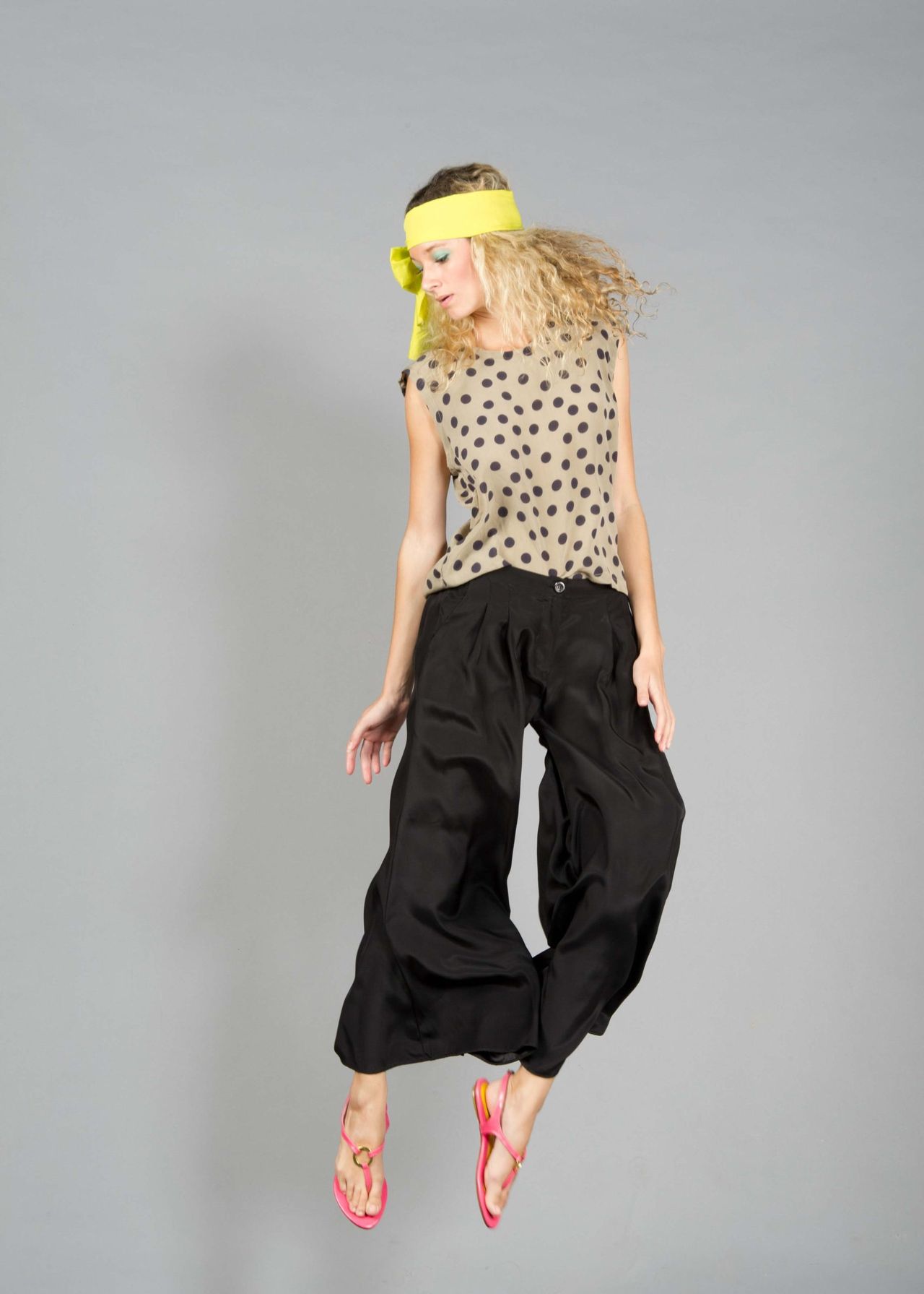 Woman in a patterned top and black trousers in a studio