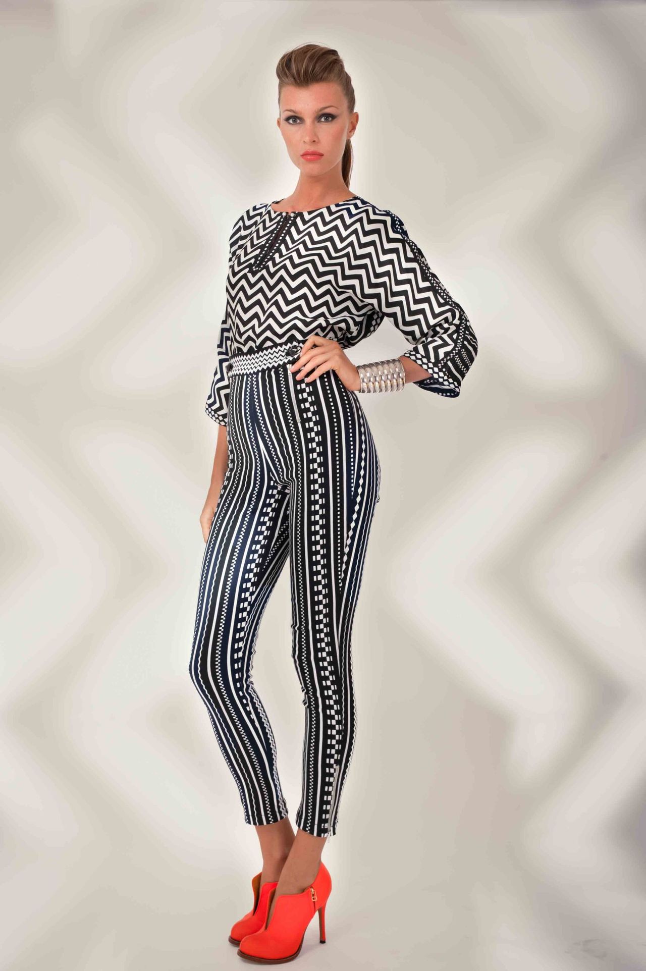 Woman in a black-and-white patterned jumpsuit and red heels