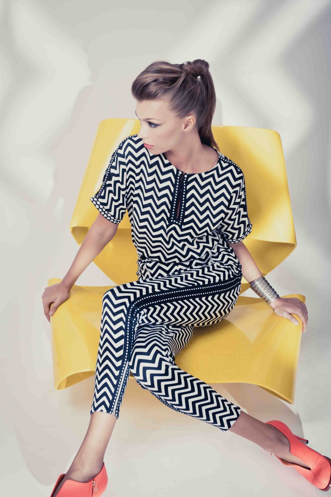 Woman in a chevron-print outfit seated in a yellow chair