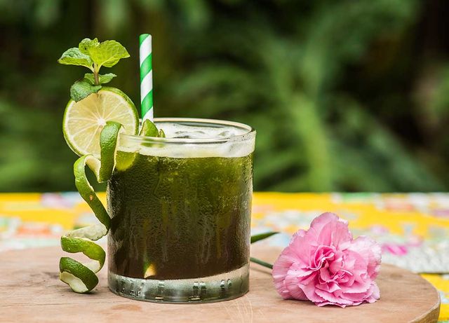 Green drink in a glass with lime slices and mint
