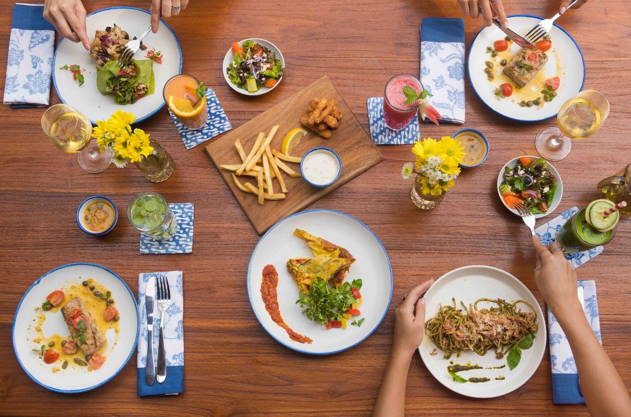 Shared table of plated dishes and drinks, seen from above