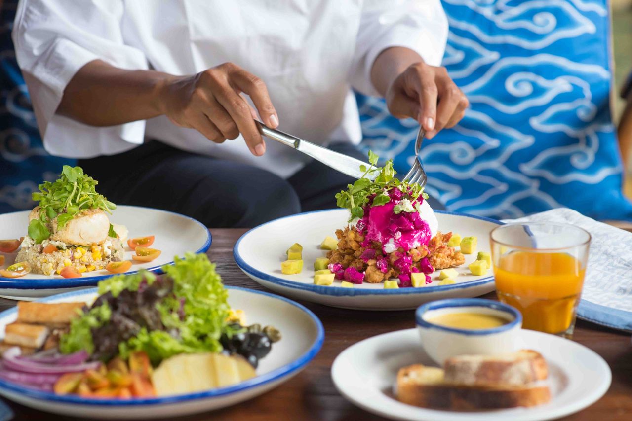 Chef plating colourful dishes with orange juice on the table