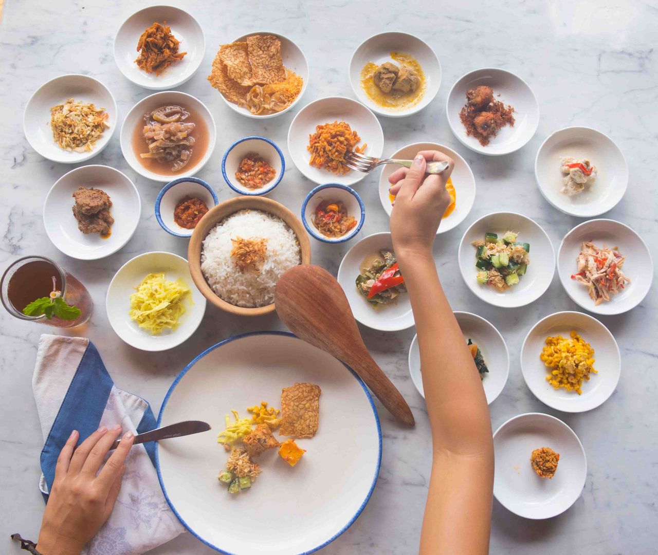 Many small bowls of food on a table, seen from above