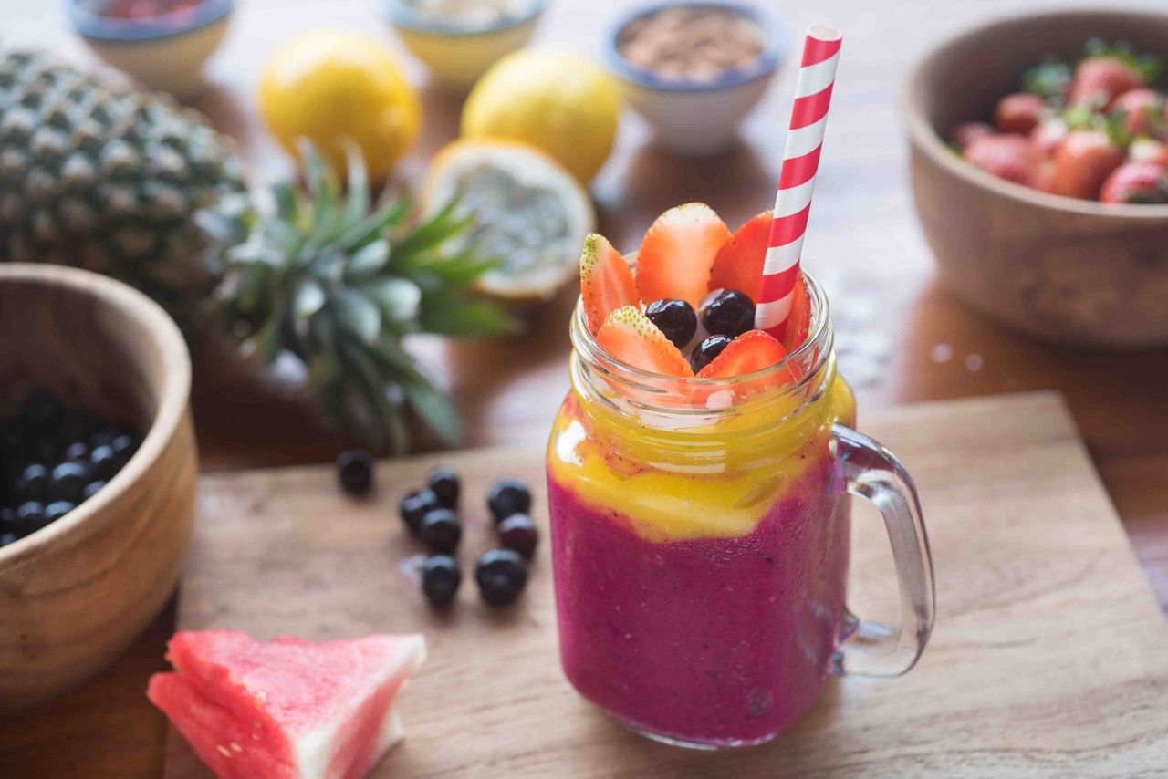 Layered pink and yellow smoothie in a jar with tropical fruit