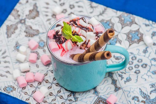 Mug of hot chocolate topped with marshmallows and wafer rolls