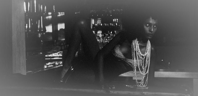 Low-key black-and-white portrait of a woman with long beaded necklaces