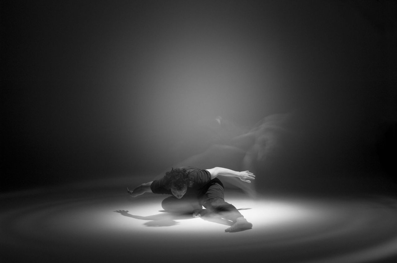 Dancer on a dark stage under a single spotlight