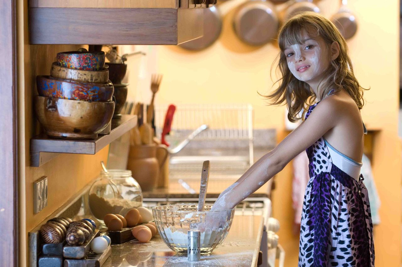 Girl in a kitchen mixing ingredients in a glass bowl