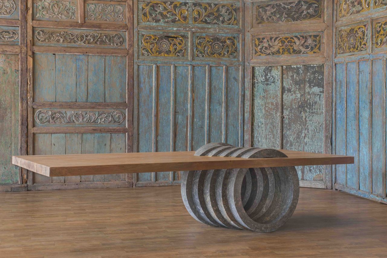 Timber bench with a coiled metal base in front of carved panels