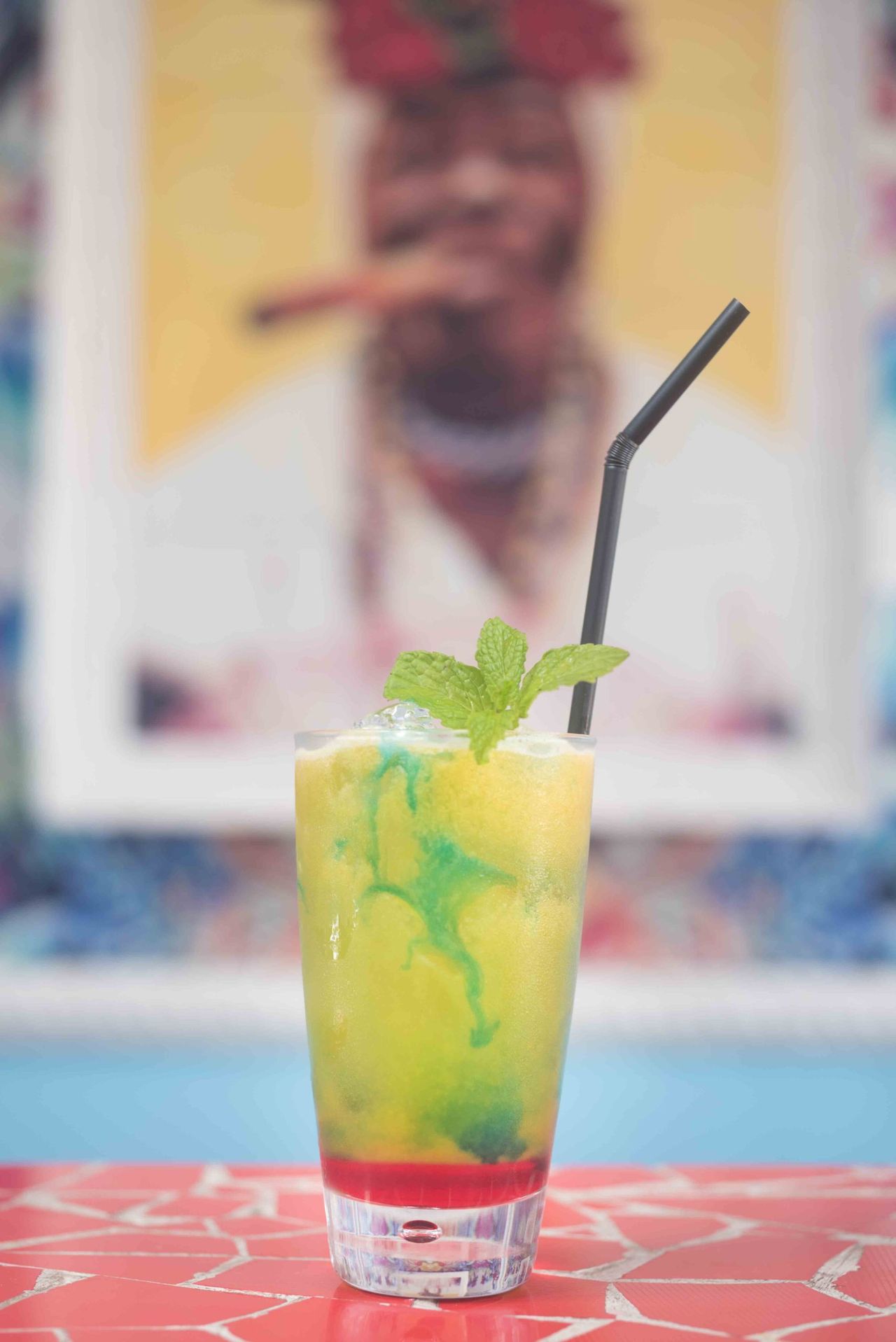 Layered yellow and green drink with mint in front of a painted mural