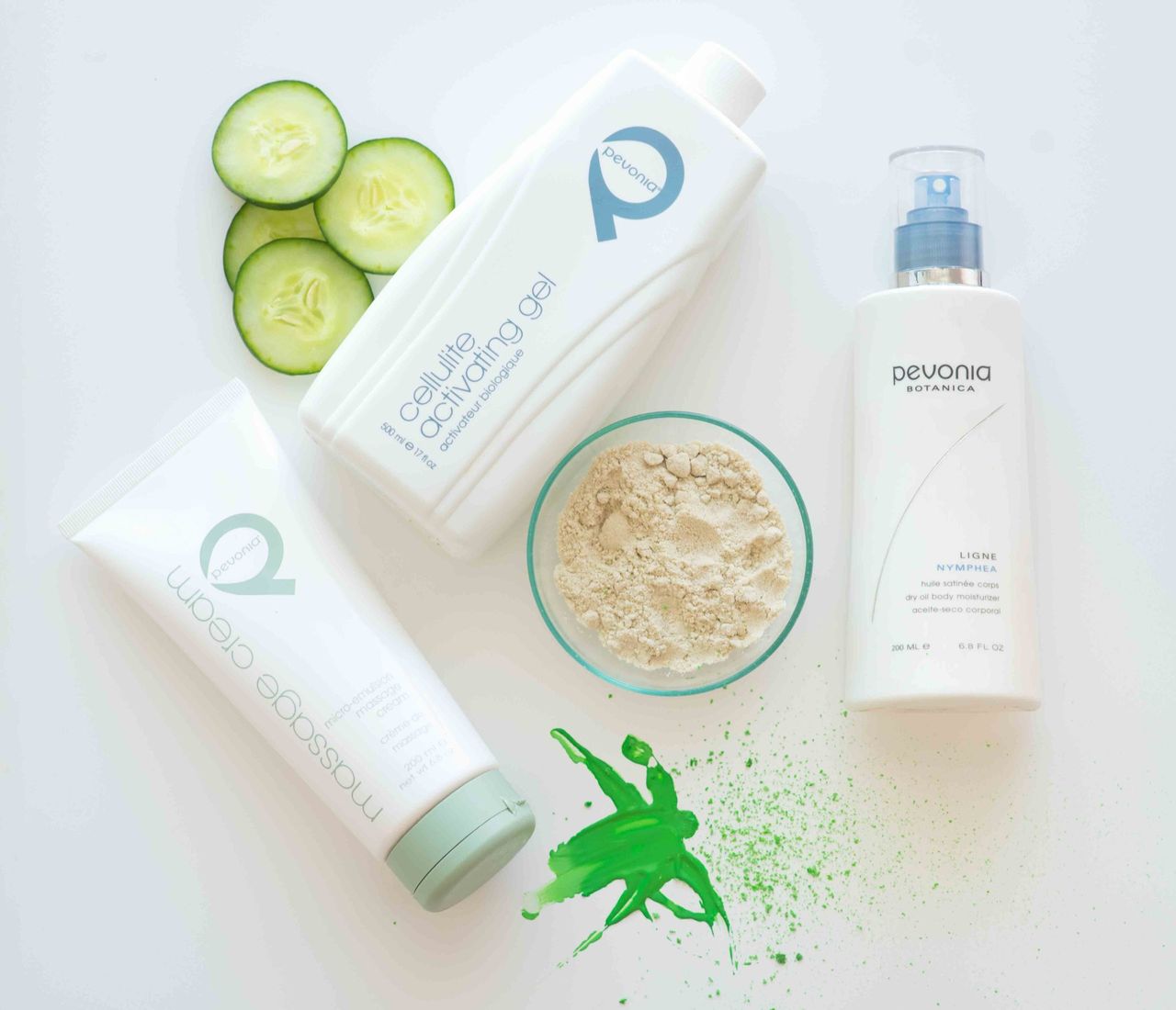 Skincare bottles and tubes with cucumber slices and a bowl of powder