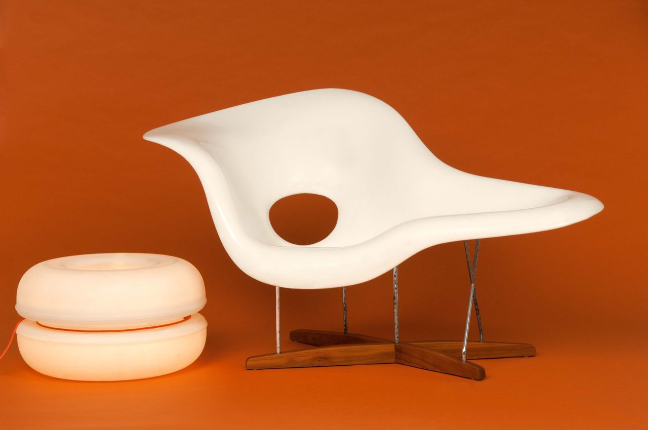 White sculptural lounge chair and a round cushion on an orange background
