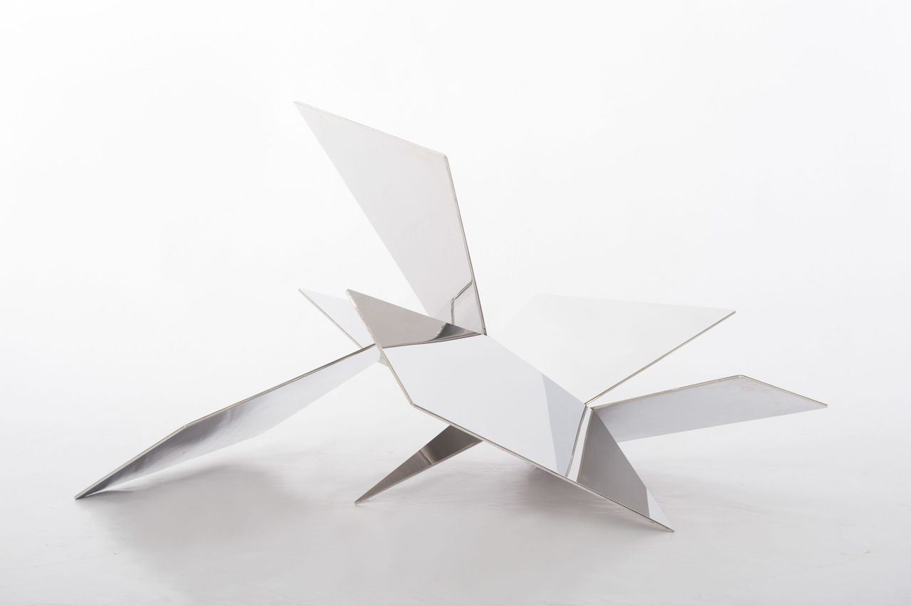 White folded-metal sculptural chair on a white background
