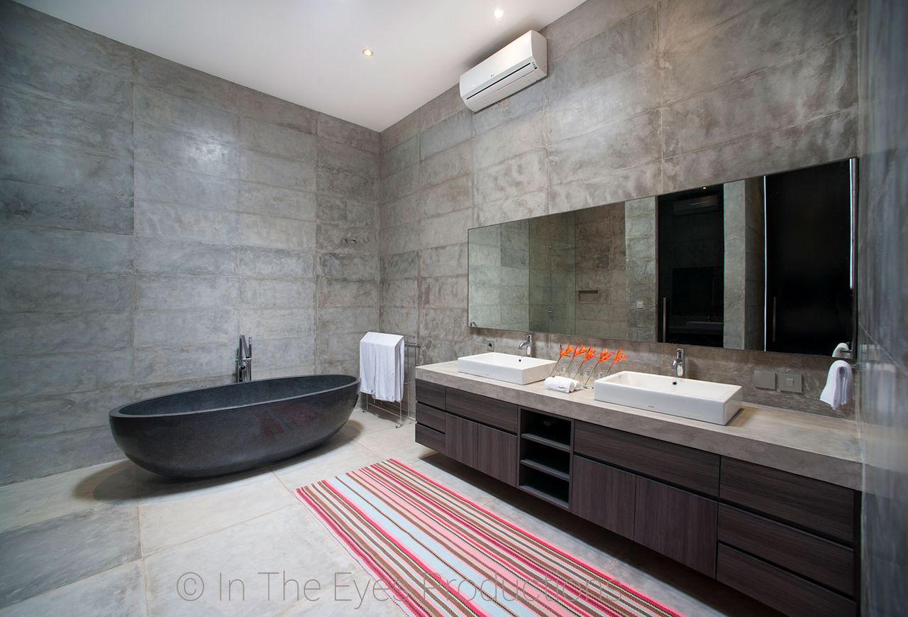 Bathroom with a black freestanding bath, double basins and concrete-look walls