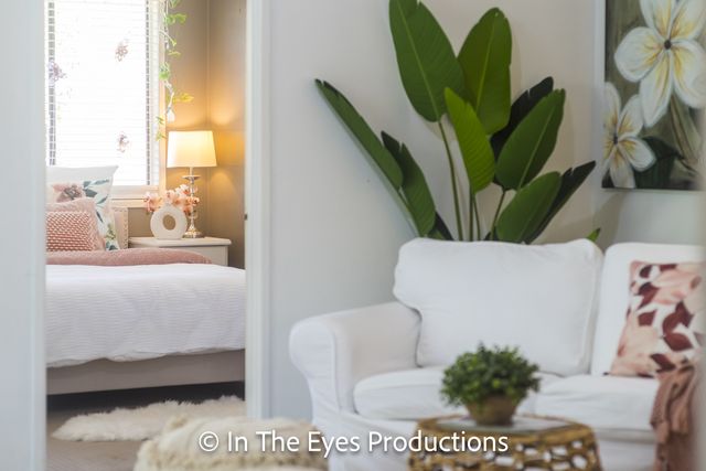 Bedroom corner with a white armchair and large tropical leaves