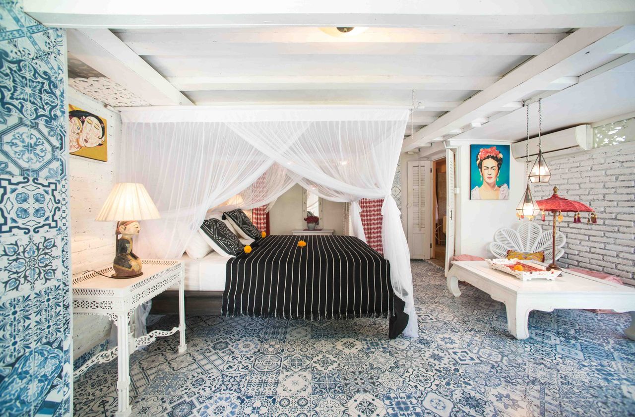 Bedroom with a white draped canopy bed and patterned blue floor tiles