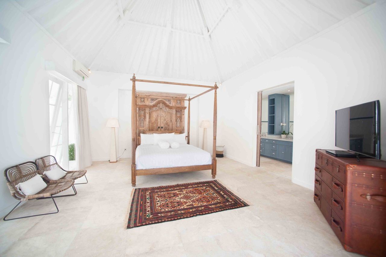 Bedroom with a carved timber four-poster bed and a red patterned rug
