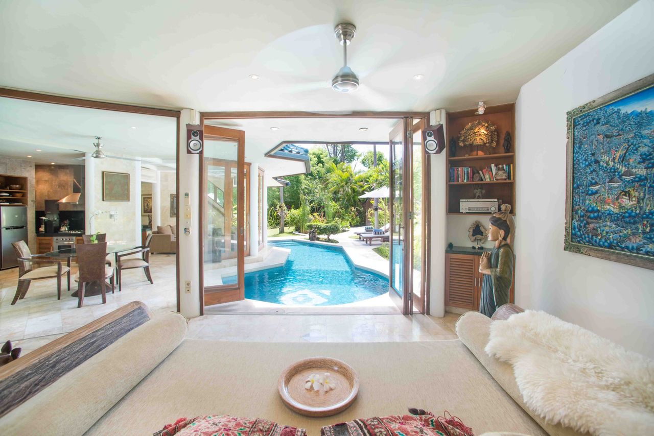 Living room opening through glass doors onto a swimming pool