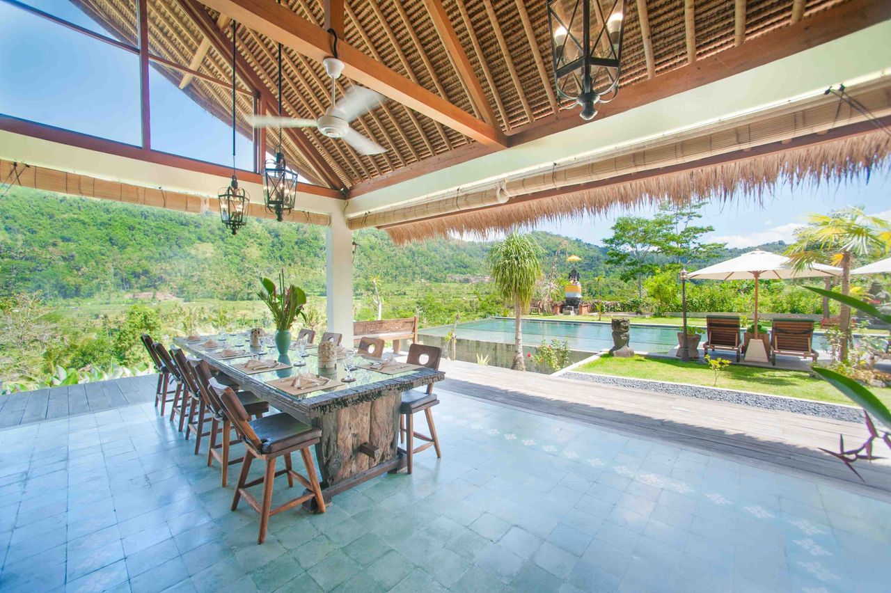 Open-air dining pavilion with a long table, looking out over green hills