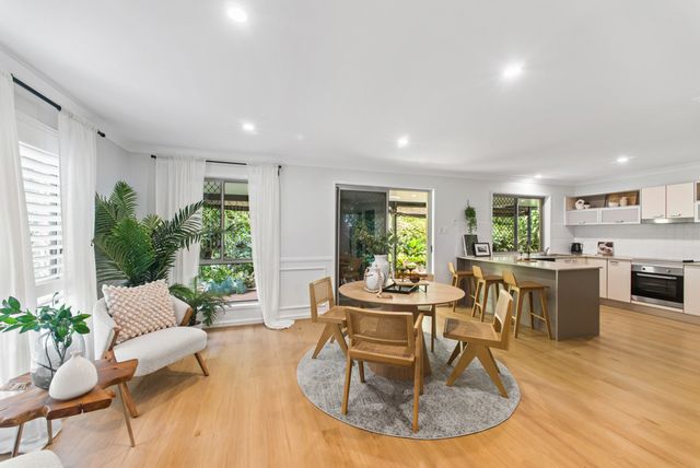 Open-plan living and dining area with a round timber table and the kitchen behind