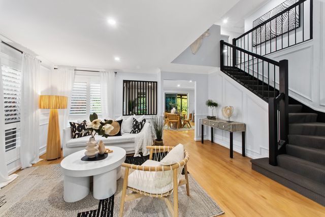 Living area with a black staircase, white sofas and timber floors