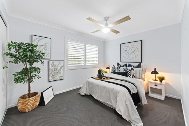 Bedroom with a potted fiddle-leaf fig, framed prints and grey carpet
