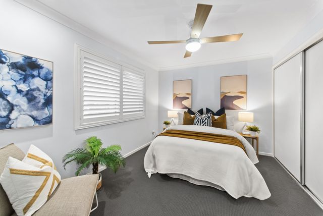 Bright bedroom with plantation shutters, a ceiling fan and blue abstract artwork