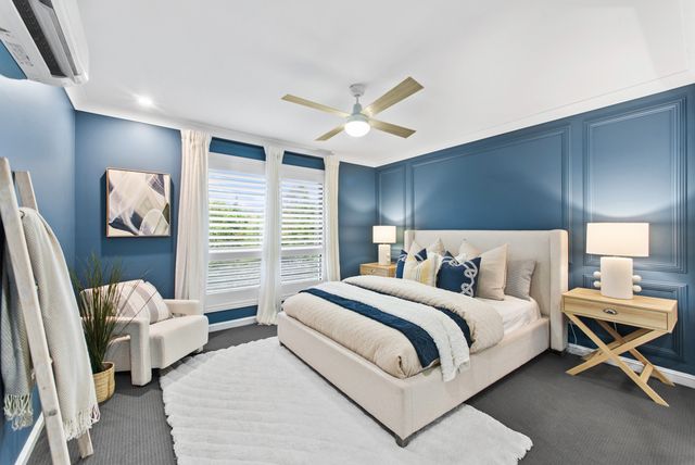 Bedroom with navy panelled walls, a ceiling fan and a white upholstered bed