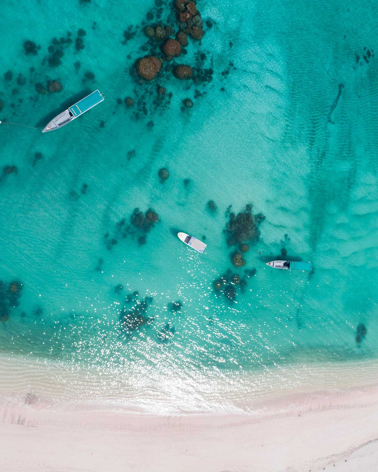 Aerial view of boats over coral patches in turquoise water