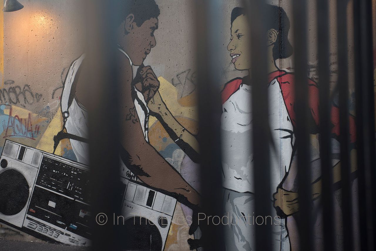 Street mural of a man and a woman with a boombox, seen through black railings