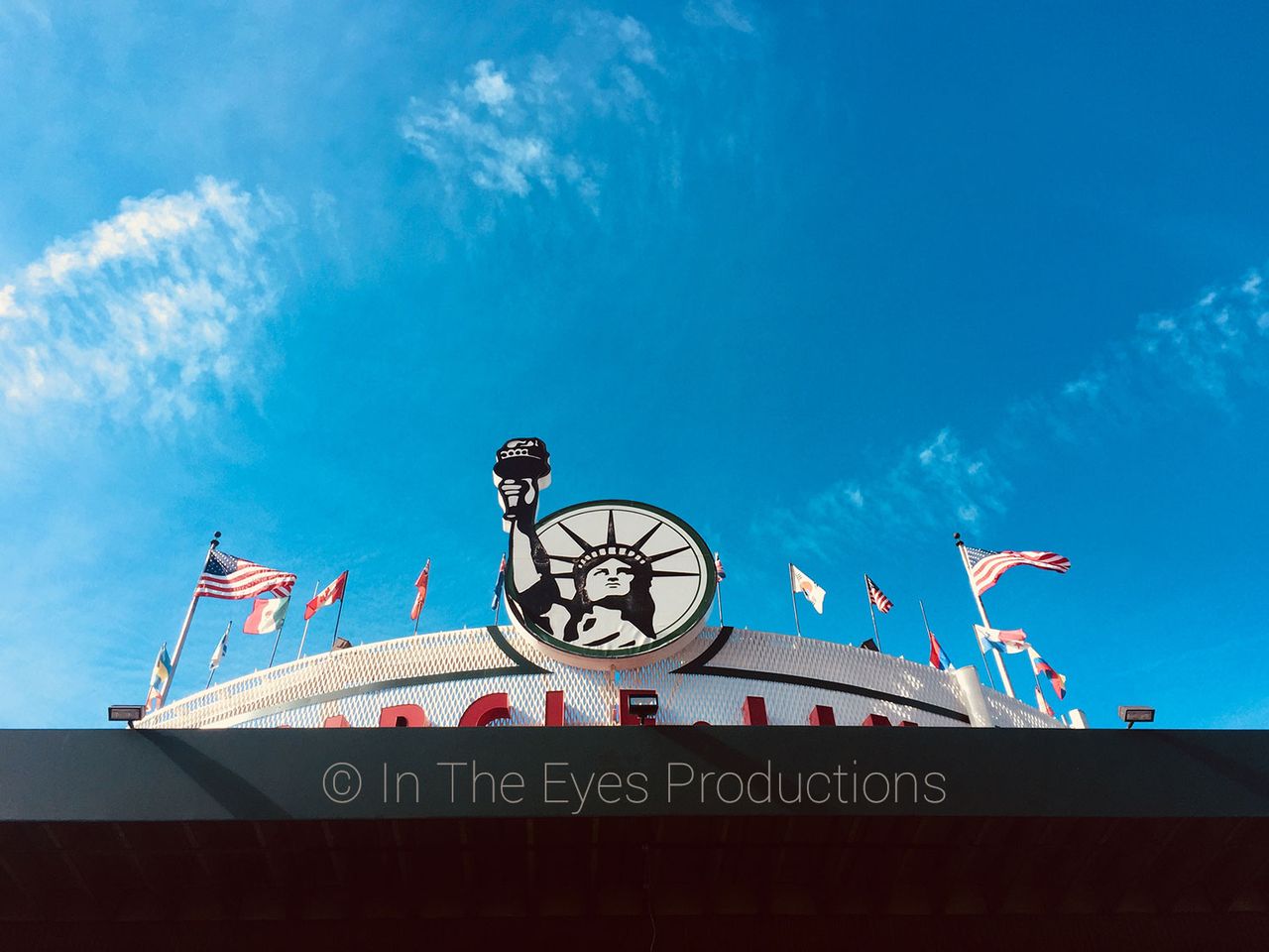 Fairground sign with flags under a bright blue sky